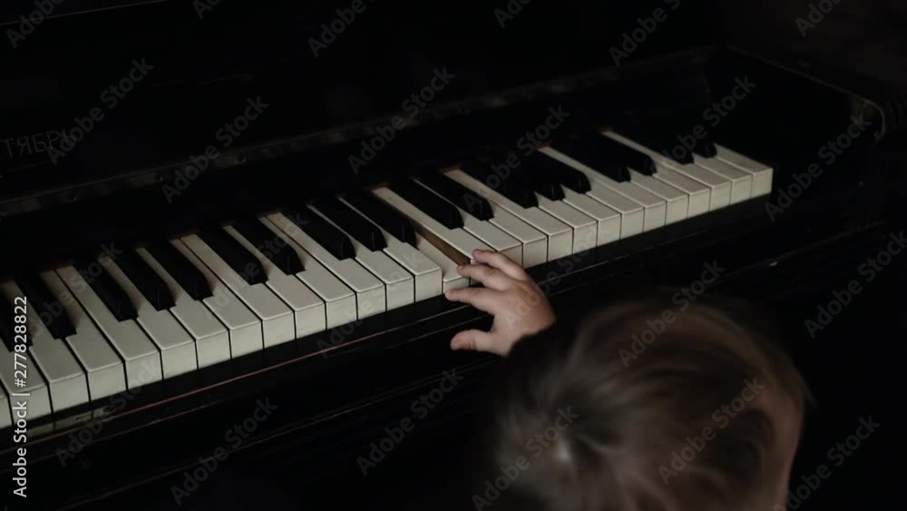 Little cute baby boy gently presses one piano key in slow motion. Child trying to play piano at home. Curious little guy. Little cute baby boy gently presses one piano key in slow motion. Child trying to play piano at home. Curious little guy.