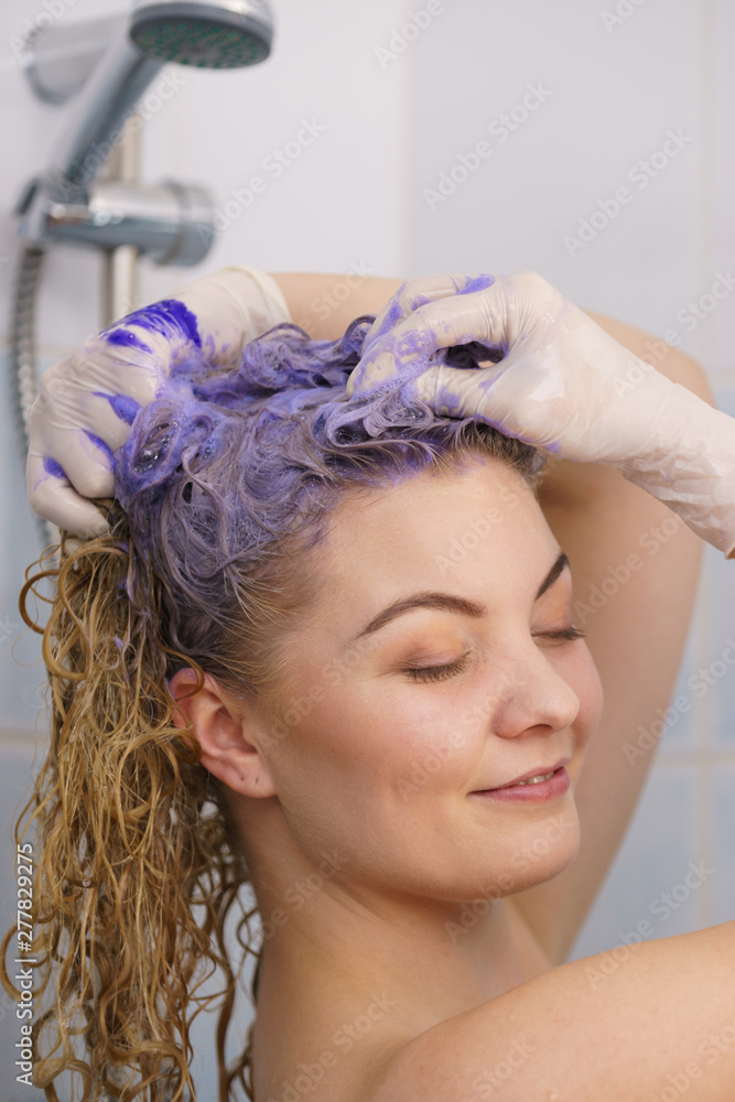 Fototapeta premium Woman applying toner shampoo on her hair