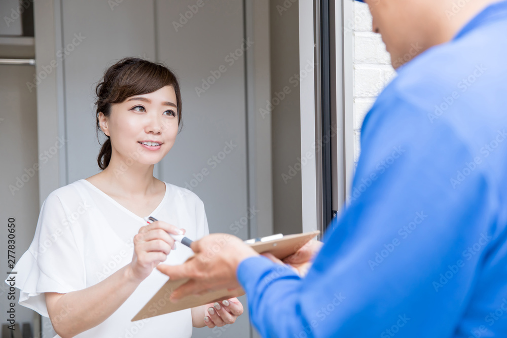 Fototapeta premium 玄関でサインする女性