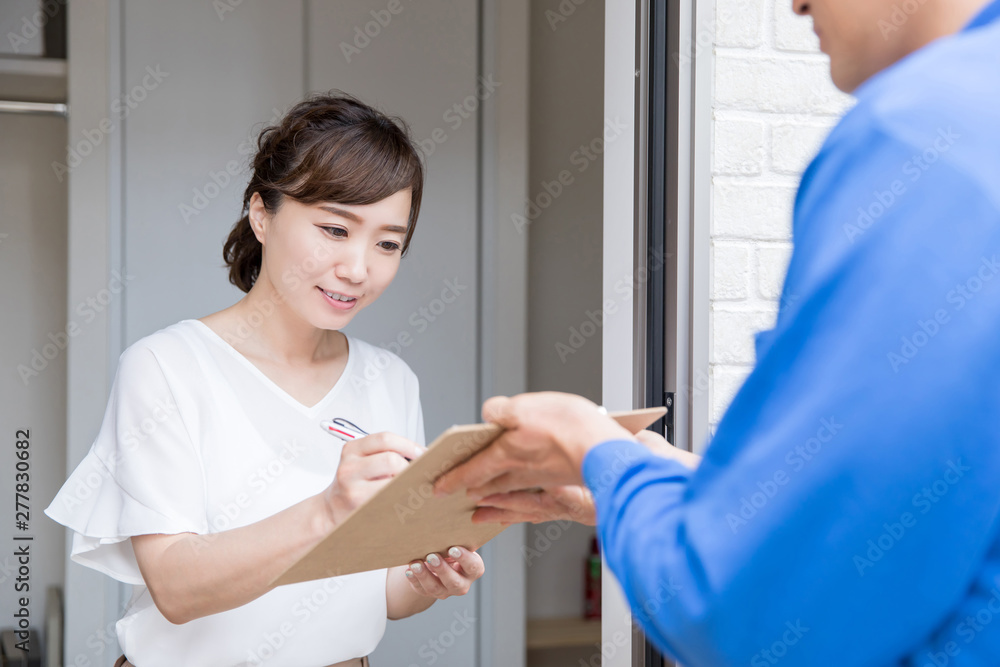玄関でサインする女性 玄関でサインする女性