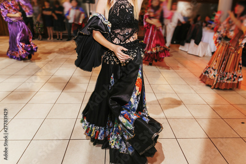 Gypsy dance festival, Woman performing romany dance and folk songs in national clothing. Beautiful roma gypsy girls dancing in traditional floral dress at wedding reception in restaurant