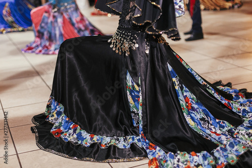 Beautiful gypsy girls dancing in traditional black floral dress at wedding reception in restaurant. Woman performing romany dance and folk songs in national clothing. Roma gypsy festival