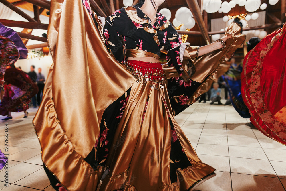 Gypsy dance festival, Woman performing romany dance and folk songs in national clothing. Beautiful roma gypsy girls dancing in traditional floral dress at wedding reception in restaurant