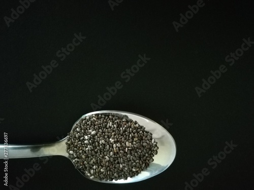 Chia seeds with a spoon on a black background.Copy space