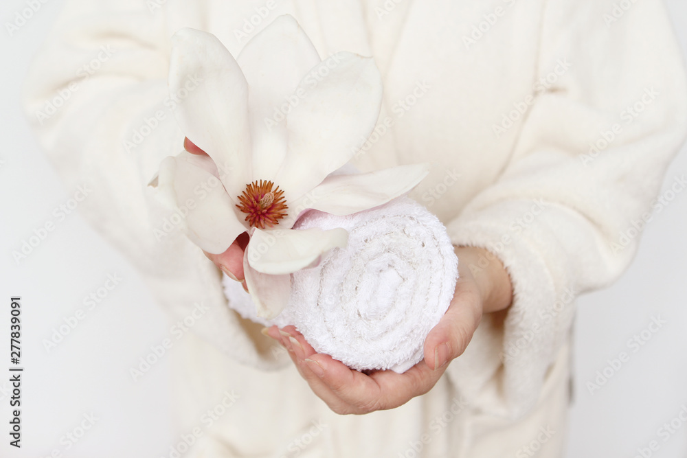 towel and magnolia flower in female hands, concept of massage, spa, on a light background, copy space towel and magnolia flower in female hands, concept of massage, spa, on a light background, copy space