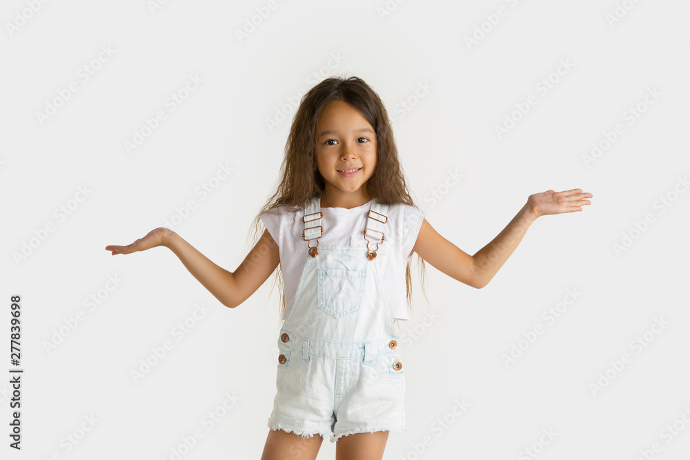 Beautiful female half-length portrait isolated on white studio background. Little emotional asian girl wearing white. Facial expression, human emotions, advertising concept. Showing, inviting.