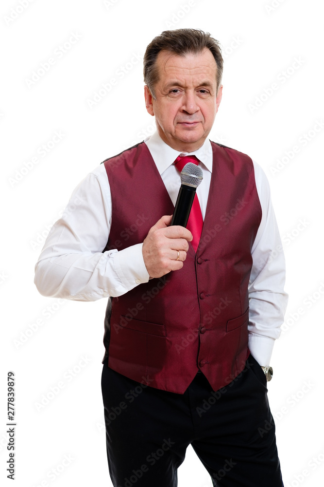 Portrait of successful senior man 55-60 years old. Male stand in beautiful vest with red tie and white shirt. Grinning male hold microphone and second hand in pocket. Isolated on white background. Portrait of successful senior man 55-60 years old. Male stand in beautiful vest with red tie and white shirt. Grinning male hold microphone and second hand in pocket. Isolated on white background.