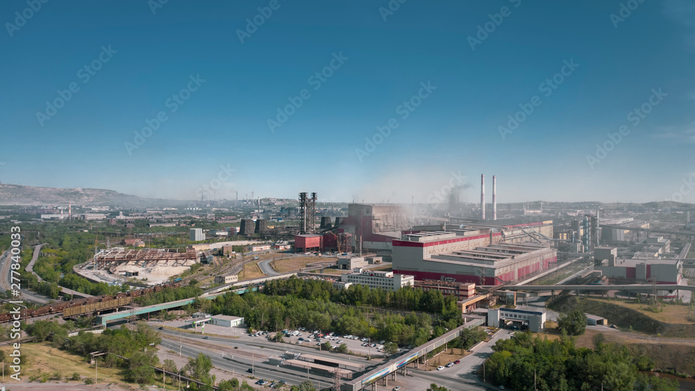 Obraz premium Concept of environmental pollution, drone view of smokestack pipe steel plant, aerial industrial panoramic landscape with blue sky and autumn vegetation, air emissions from manufacturing sector,Russia