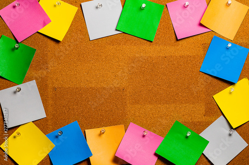 Corkboard/Bulletin Board bordered completely by very disorderly  multicolored stiky type square notes.  The notes are all blank and easily edited with copy and the center is open for copywriting. photo