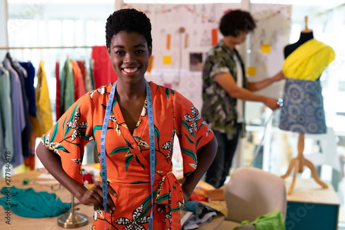 Female fashion designer standing with hands on hip in design studio