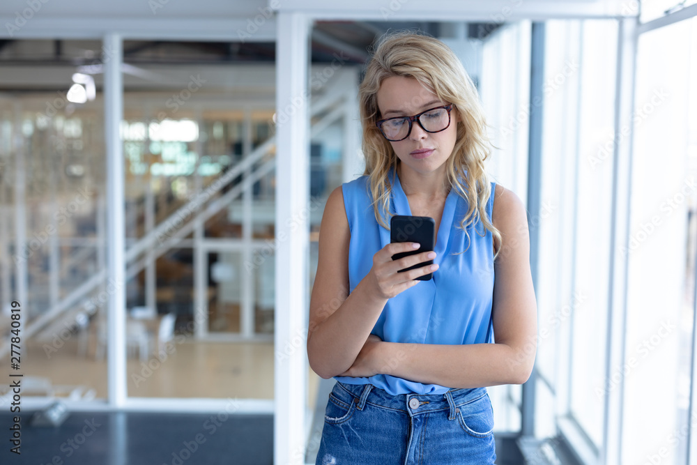 Fototapeta premium Beautiful businesswoman using mobile phone in a modern office