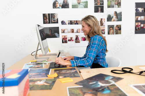 Female fashion designer using graphic tablet at desk