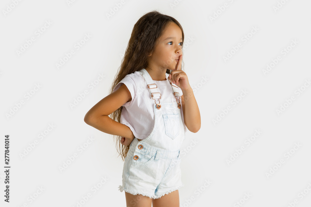 Beautiful female half-length portrait isolated on white studio background. Little emotional asian girl wearing white. Facial expression, human emotions, advertising, sales concept. Whispering a secret Beautiful female half-length portrait isolated on white studio background. Little emotional asian girl wearing white. Facial expression, human emotions, advertising, sales concept. Whispering a secret