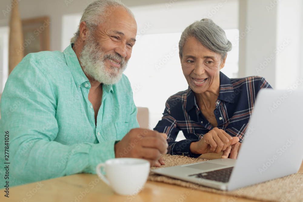 Couple using laptop on table inside a room Couple using laptop on table inside a room