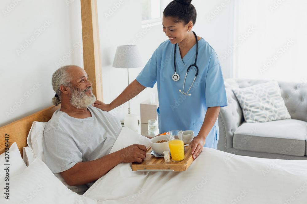 Fototapeta premium Healthcare worker talking with old man in bed