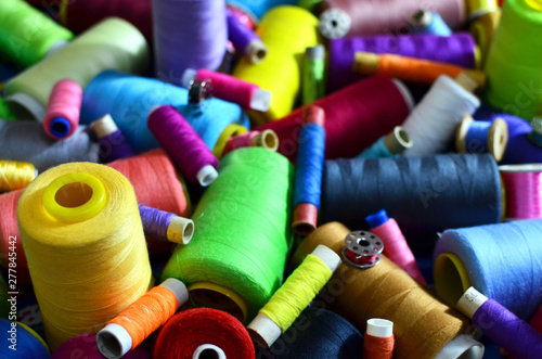 Background of bobbins with multicolored threads for sewing. Needlework, sewing and tailoring concept. Fabric and textile industry