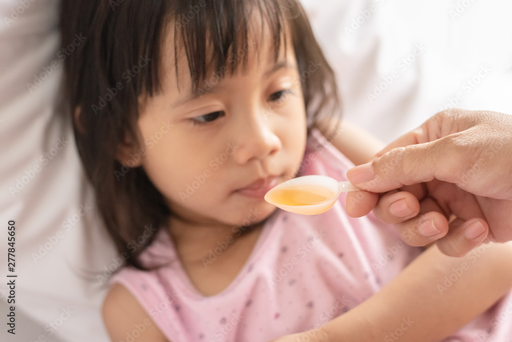 Unhappy asain girl when taking medicine syrup from her mother Unhappy asain girl when taking medicine syrup from her mother