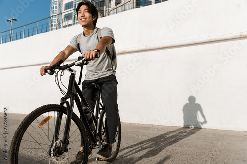 Smiling asian man riding a bicycle outdoors