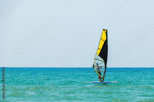 Windsurfing on the background of the sea landscape and clear sky, windsurfer men go in for sports, copy space.