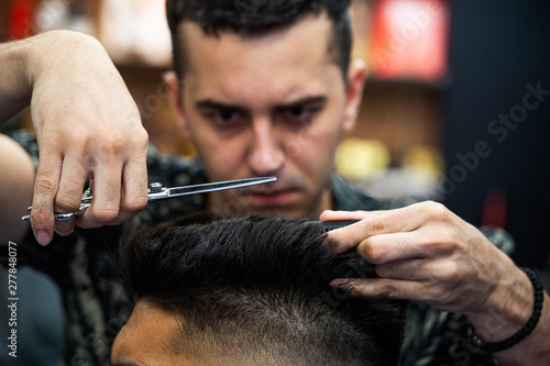 Barbershop. Close-up of man haircut, master does the hair styling in barber shop. Close-up, master Barber does the hairstyle and styling with scissors. Concept Barbershop.