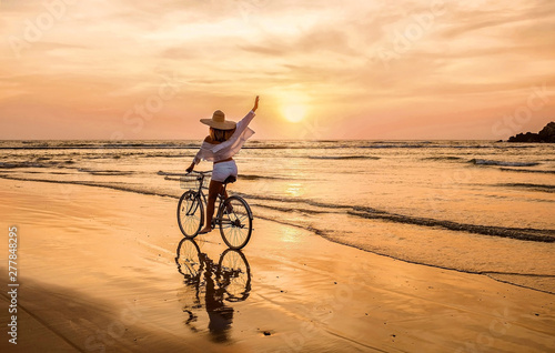 Happiness woman traveler with her bicycle rides on sea coastline