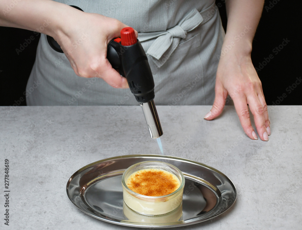 An image of a creme brulee in a transparent glass bowl on an iron tray; a