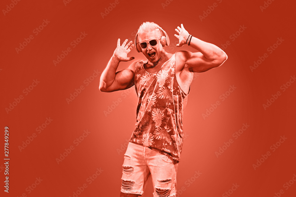 Fashion Excited DJ man dance with expression in neon coral light. Sexy emotional Handsome pumped-up blonde guy listen to music. Art neon fashionable style. Music festival nightclub, party concept Fashion Excited DJ man dance with expression in neon coral light. Sexy emotional Handsome pumped-up blonde guy listen to music. Art neon fashionable style. Music festival nightclub, party concept