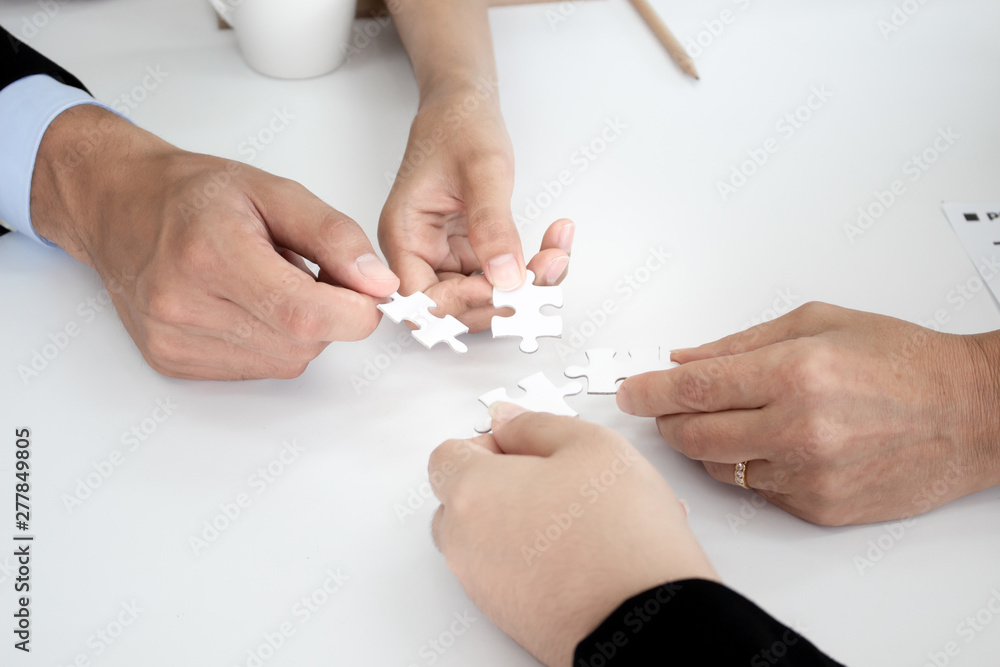 Closeup of businesspeople holding jigsaw puzzle. Closeup of businesspeople holding jigsaw puzzle.