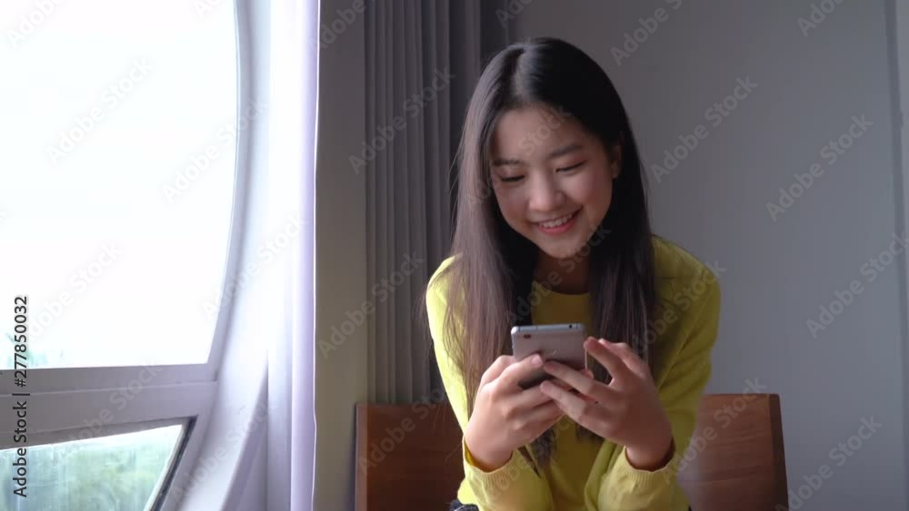 Beautiful Asian happy traveler woman in hotel room her using smartphone and take photo near windows sea view. Beautiful Asian happy traveler woman in hotel room her using smartphone and take photo near windows sea view.
