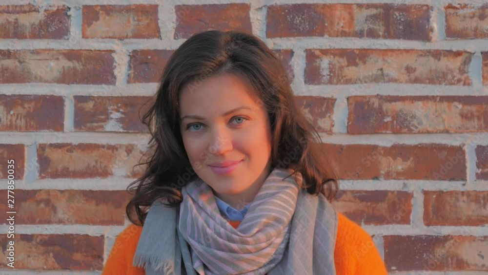 Portrait of a young beautiful smiling woman near brick wall, close-up. Portrait of a young beautiful smiling woman near brick wall, close-up.
