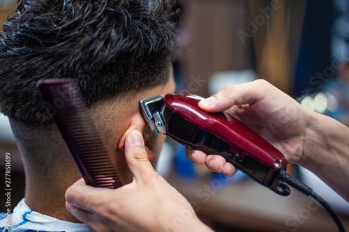 Fotografie Close up shot of man getting trendy haircut at barber shop