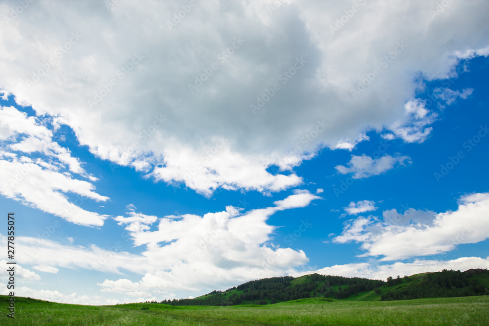 Blue sky with white clouds, fields and meadows with green grass, on the background of mountains. Composition of nature. Rural summer landscape. Blue sky with white clouds, fields and meadows with green grass, on the background of mountains. Composition of nature. Rural summer landscape.