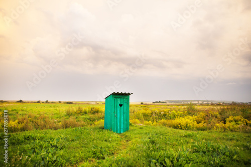 Фотография wooden toilet with a carved window in the shape of a heart, an open field