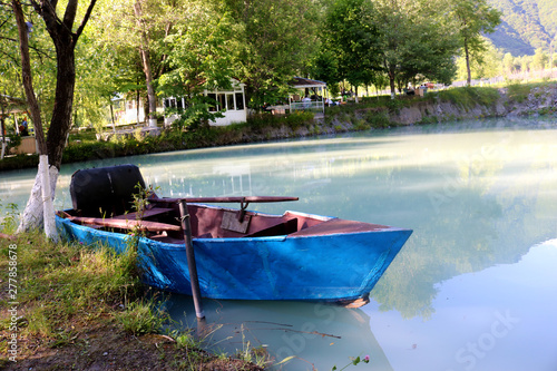 Fototapeta Naklejka Na Ścianę i Meble -  Blue boat with rake on the lake