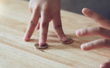 Cropped chot of kid fingers on pound coins, children counting pound coins on wooden table, Kid learning about money coins, Children learning about financial responsibility or planning savings concept.