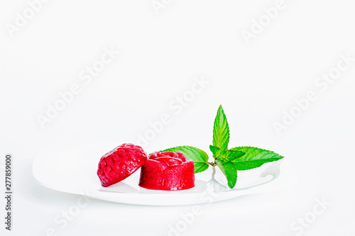 Fotografie Berry jelly with a sprig of mint on a white plate close-up.