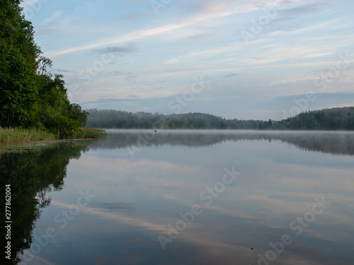 Fototapeta Naklejka Na Ścianę i Meble -  Foggy and mystical lake landscape before sunrise. All silhouettes are blurry and unclear. Vaidavas lake, Latvia