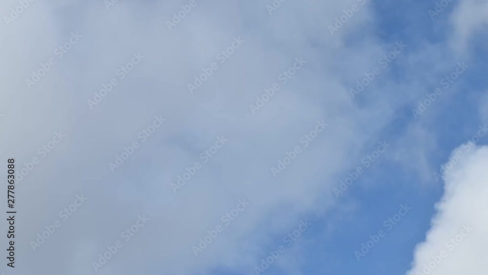 Fluffy clouds moving fast on the blue sky