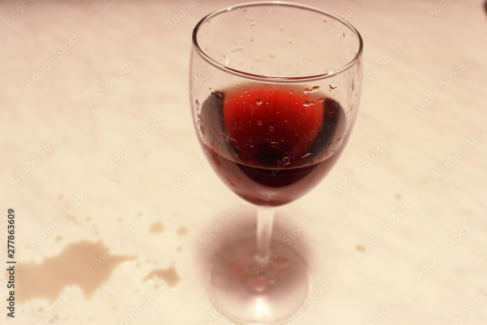  A glass of red wine on the marble table. Wine drops on the marble table.
