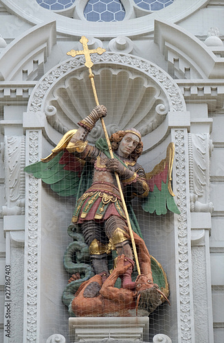 Saint Michael slaying the dragon, statue on the portal of the church of St. Leodegar in Lucerne, Switzerland photo