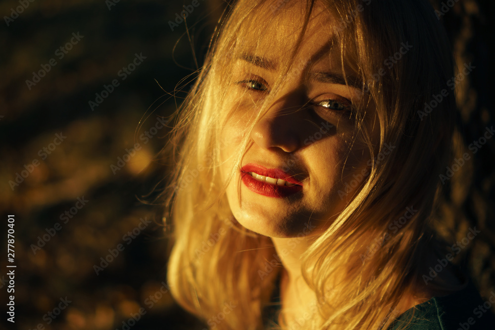 Autumn portrait of young girl with red lips at sunset
