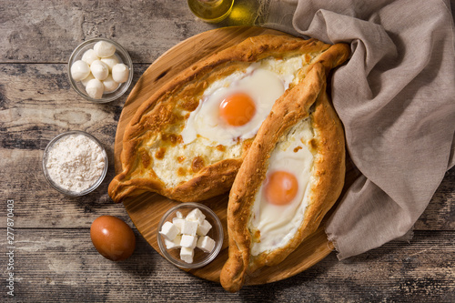 Traditional Adjarian Georgian khachapuri with cheese and egg on wooden table. Top view