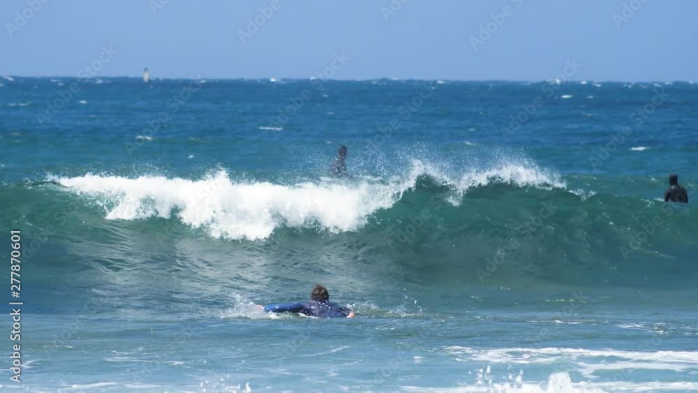 SLOW MOTION Male surfer duck diving under a small blue wave