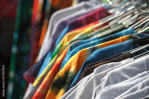 Close-up of multi-colored T-shirts hanging on hangers in the street, fair, secondhand, recycling concept