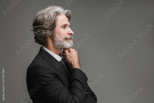 Image in profile of unshaven adult businessman wearing formal black suit looking aside at copyspace