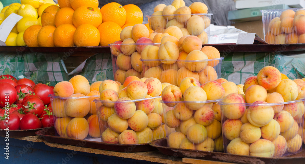 Containers with different ripe berries and fruit at market