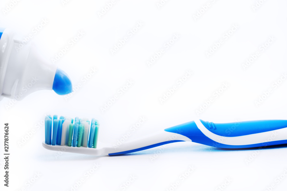 Close up view of transparent toothbrush with blue bristles and toothpaste on white background. Healthy teeth, dental care concept. Space for text. Close up view of transparent toothbrush with blue bristles and toothpaste on white background. Healthy teeth, dental care concept. Space for text.