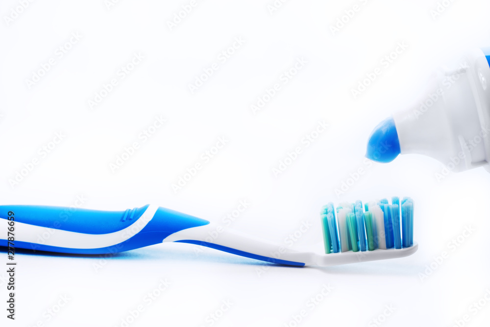 Close up view of transparent toothbrush with blue bristles and toothpaste on white background. Healthy teeth, dental care concept. Space for text. Close up view of transparent toothbrush with blue bristles and toothpaste on white background. Healthy teeth, dental care concept. Space for text.