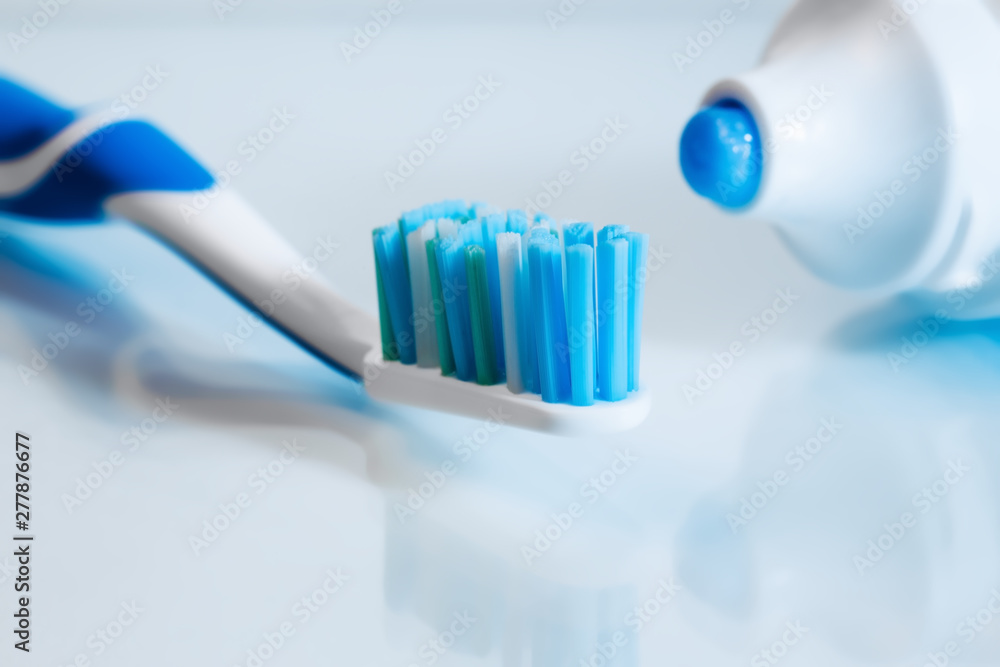 Close up view of transparent toothbrush with blue bristles and toothpaste on white background. Healthy teeth, dental care concept. Space for text. Close up view of transparent toothbrush with blue bristles and toothpaste on white background. Healthy teeth, dental care concept. Space for text.