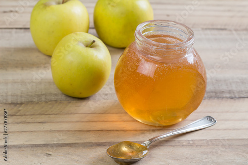 Apple jelly in a jar and apples on wooden background